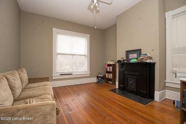 living area with baseboards, a ceiling fan, and hardwood / wood-style floors