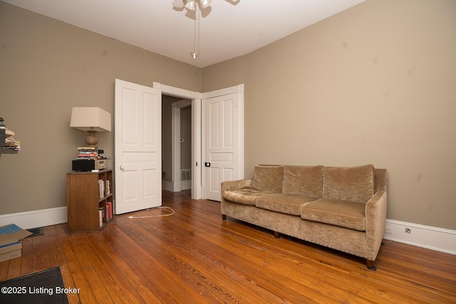 living area featuring baseboards, ceiling fan, and hardwood / wood-style flooring
