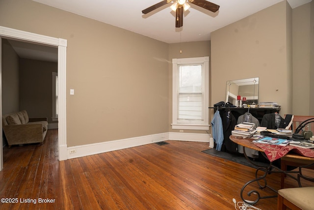 interior space with baseboards, visible vents, ceiling fan, and hardwood / wood-style floors