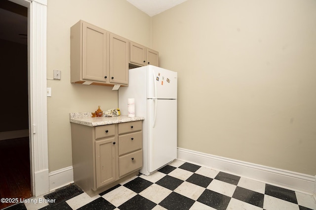 kitchen featuring baseboards, light countertops, freestanding refrigerator, and light floors
