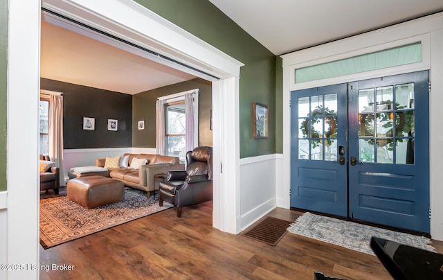 foyer entrance featuring dark wood finished floors, french doors, wainscoting, and visible vents