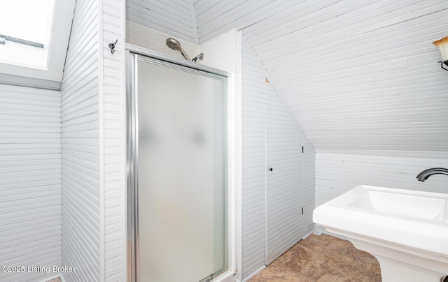 bathroom with a sink, a stall shower, and lofted ceiling