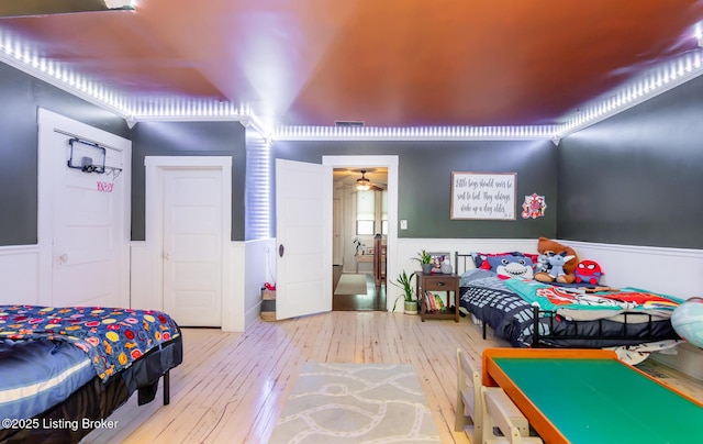 bedroom with wood-type flooring, wainscoting, and visible vents