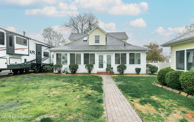 bungalow featuring fence, roof with shingles, a sunroom, and a front lawn