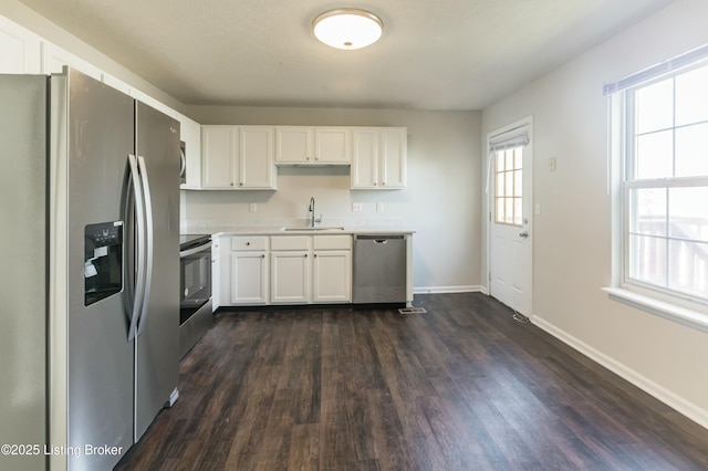 kitchen featuring light countertops, a sink, white cabinetry, appliances with stainless steel finishes, and baseboards