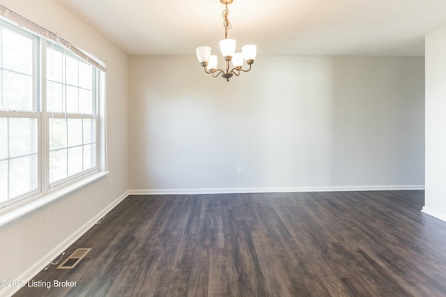 unfurnished room with baseboards, a notable chandelier, visible vents, and dark wood-style flooring
