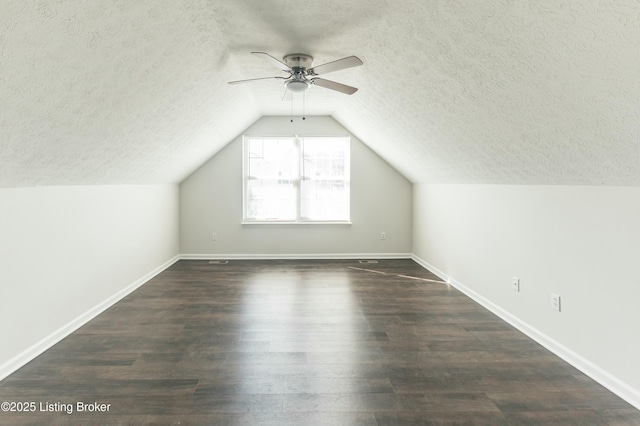 additional living space with baseboards, lofted ceiling, ceiling fan, and dark wood-style flooring