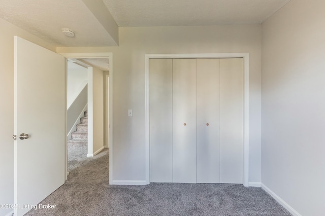 unfurnished bedroom featuring carpet flooring, baseboards, and a closet