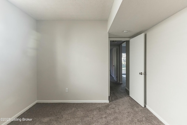 carpeted empty room featuring baseboards and a textured ceiling