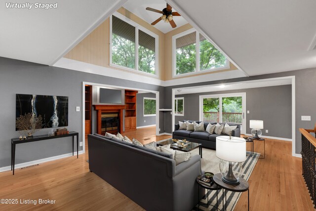 1468 Lakeshore Pkwy, Brandenburg, KY 40108 - living room with ceiling fan, a towering ceiling, light wood finished floors, and a glass covered fireplace
