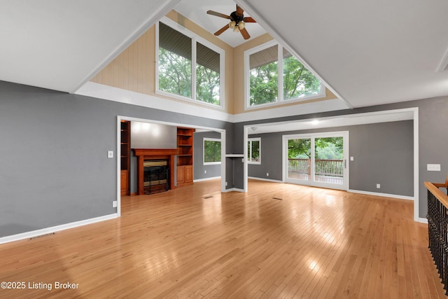 1468 Lakeshore Pkwy, Brandenburg, KY 40108 - unfurnished living room with ceiling fan, a towering ceiling, a glass covered fireplace, and light wood finished floors
