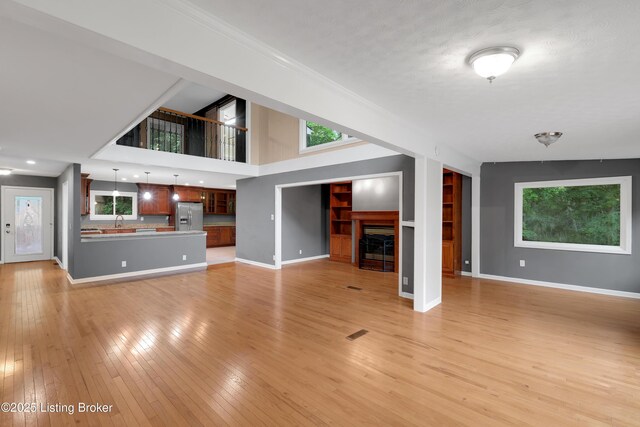 1468 Lakeshore Pkwy, Brandenburg, KY 40108 - unfurnished living room featuring light wood-style floors, built in shelves, a fireplace, and crown molding