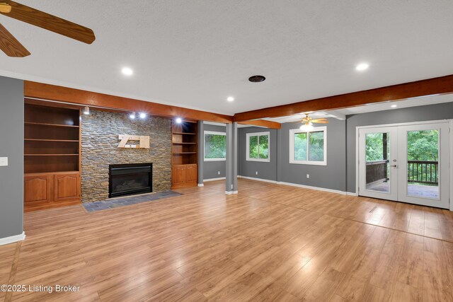 1468 Lakeshore Pkwy, Brandenburg, KY 40108 - unfurnished living room with ceiling fan, a stone fireplace, light wood-type flooring, built in features, and french doors
