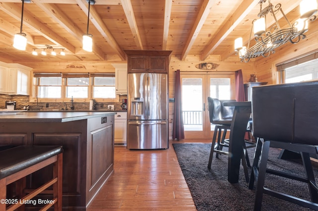 kitchen with dark wood-style floors, wood ceiling, stainless steel refrigerator with ice dispenser, and wood walls