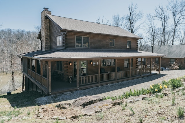 view of front of property featuring log siding, a chimney, a shingled roof, and a porch