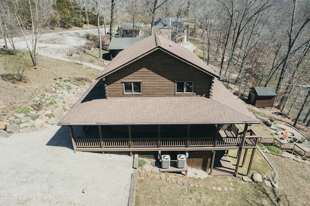view of front of home featuring log siding, central air condition unit, and roof with shingles