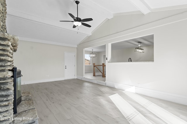 unfurnished living room featuring ceiling fan with notable chandelier, wood finished floors, vaulted ceiling with beams, and baseboards