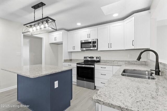kitchen with light wood-style flooring, stainless steel appliances, a sink, light stone counters, and white cabinets