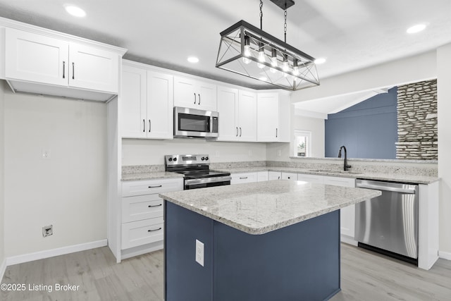 kitchen with a kitchen island, a sink, light wood-style floors, white cabinets, and appliances with stainless steel finishes