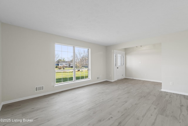 unfurnished room with wood finished floors, baseboards, and visible vents