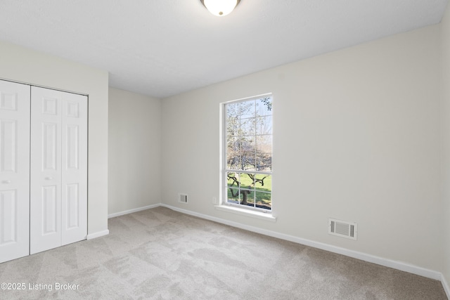 unfurnished bedroom with baseboards, visible vents, a closet, and carpet floors