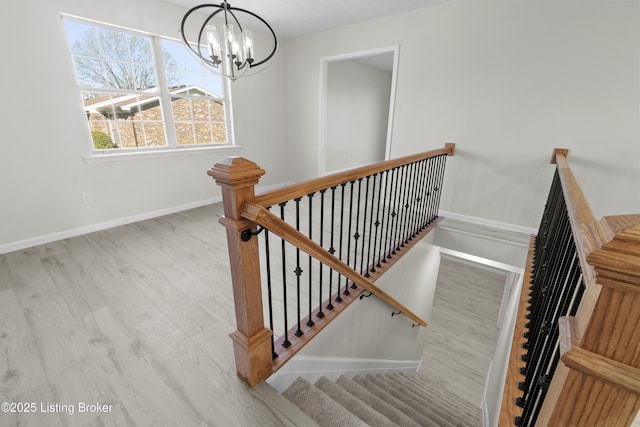 stairs with baseboards, wood finished floors, and a chandelier