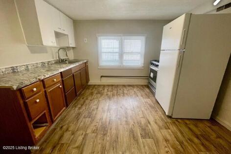 kitchen with freestanding refrigerator, a sink, stainless steel range with gas cooktop, and wood finished floors