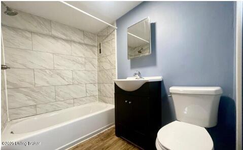 full bath featuring toilet, shower / tub combination, wood finished floors, and vanity