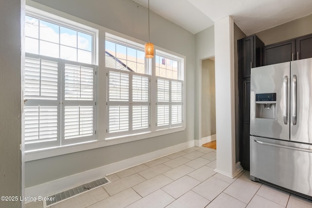 kitchen featuring light tile patterned flooring, visible vents, baseboards, stainless steel refrigerator with ice dispenser, and decorative light fixtures