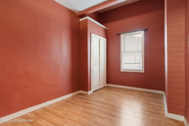 unfurnished bedroom featuring baseboards, a closet, and light wood-style flooring
