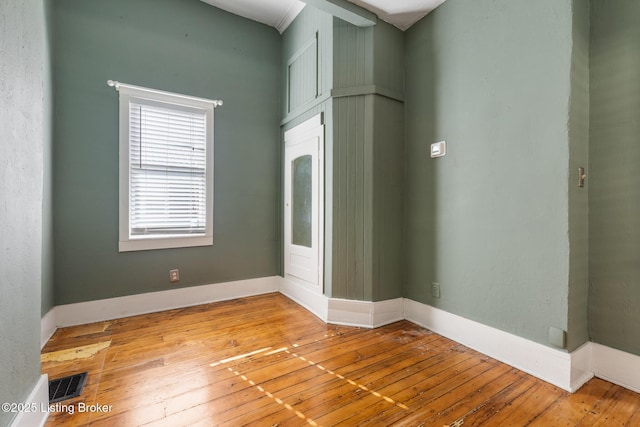 empty room with baseboards, visible vents, and light wood-type flooring