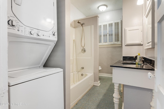 bathroom featuring stacked washer and clothes dryer, shower / bath combination, vanity, toilet, and baseboards