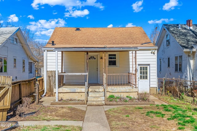 bungalow with covered porch, fence, and a shingled roof