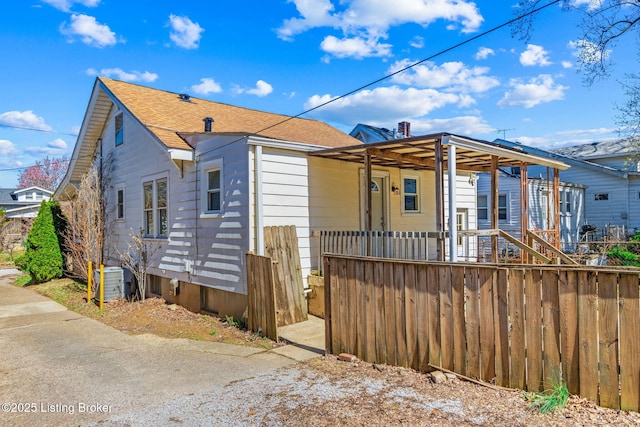 view of front of property with roof with shingles, a porch, a fenced front yard, and central air condition unit