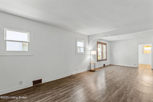 unfurnished room featuring baseboards, visible vents, and wood finished floors