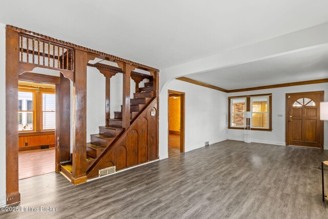 entrance foyer featuring stairs, wood finished floors, baseboards, visible vents, and arched walkways