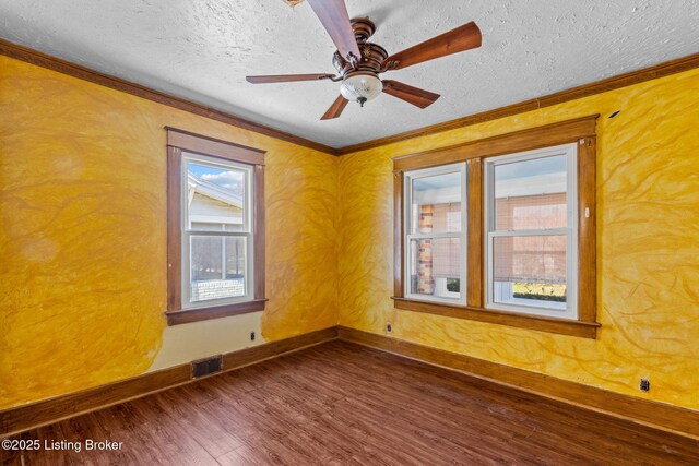 empty room with dark wood-style floors, crown molding, and visible vents