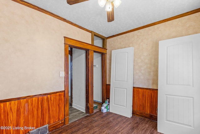 spare room with a ceiling fan, wood finished floors, wainscoting, visible vents, and ornamental molding