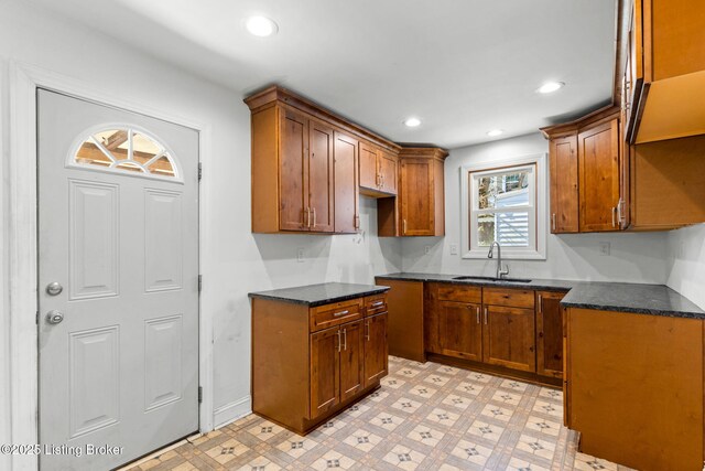 kitchen featuring recessed lighting, brown cabinetry, light floors, and a sink