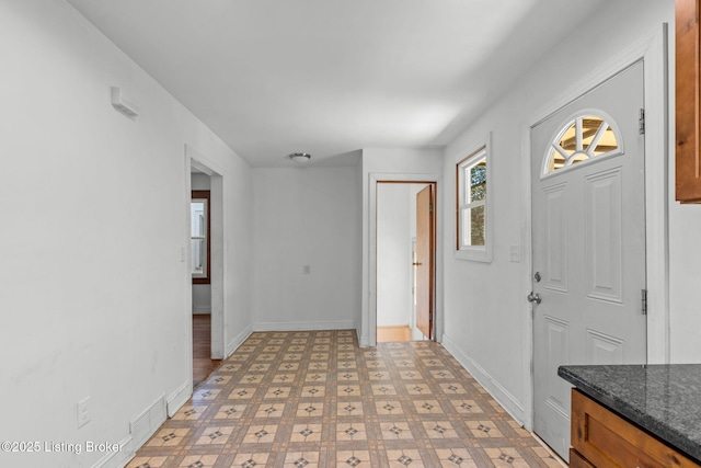 foyer with baseboards and light floors