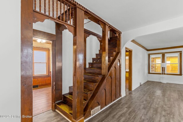stairway with baseboards, arched walkways, visible vents, and wood finished floors