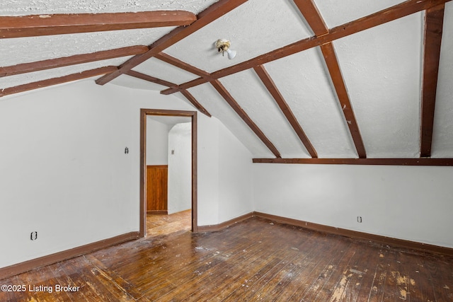 additional living space featuring hardwood / wood-style floors, baseboards, vaulted ceiling, and a textured ceiling