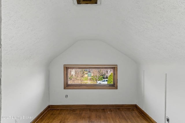 bonus room featuring dark wood-style floors, lofted ceiling, baseboards, and a textured ceiling