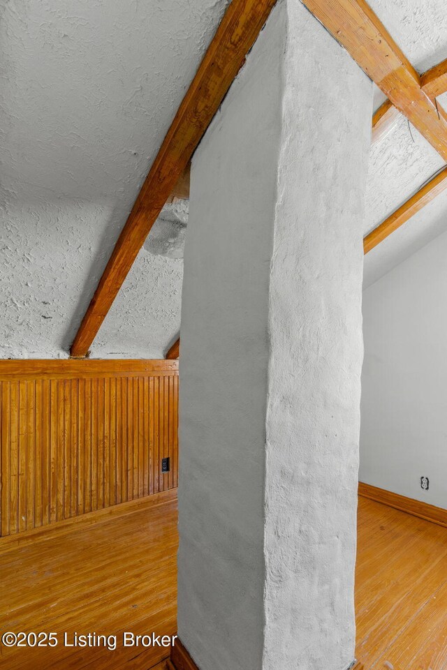 room details featuring baseboards, a textured ceiling, beamed ceiling, and wood finished floors