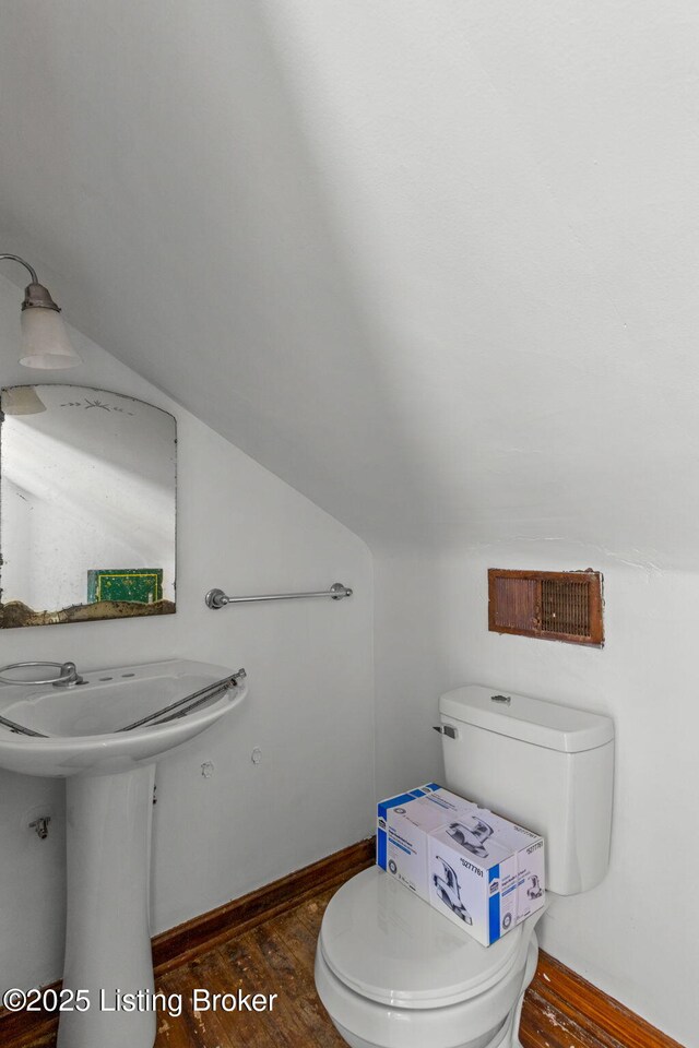 bathroom featuring toilet, lofted ceiling, wood finished floors, and baseboards