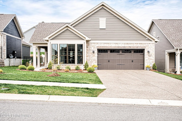 craftsman inspired home with a front yard, driveway, and stone siding