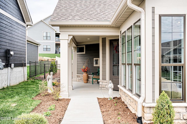 doorway to property featuring fence and a shingled roof