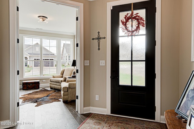 foyer featuring ornamental molding, a wealth of natural light, baseboards, and dark wood finished floors