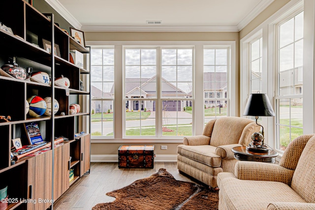 living area featuring visible vents, baseboards, crown molding, and wood finished floors