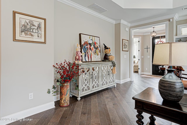 hallway featuring crown molding, hardwood / wood-style floors, baseboards, and visible vents